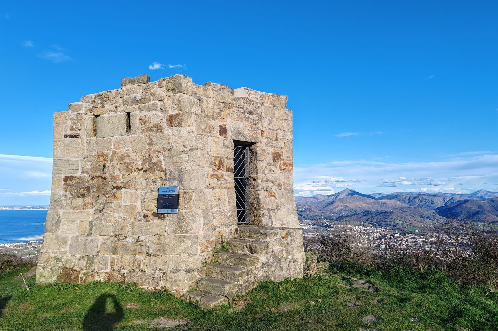 A stone tower on Jaizkibel, with the coast and mountains beyond